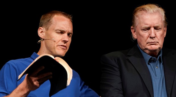 U.S. President Donald Trump stands on stage as Pastor David Platt prays for him at the McLean Bible Church, in Vienna, Virginia.