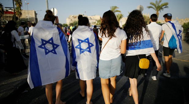 Jewish youth covered with Israeli flags as they participate in a march marking