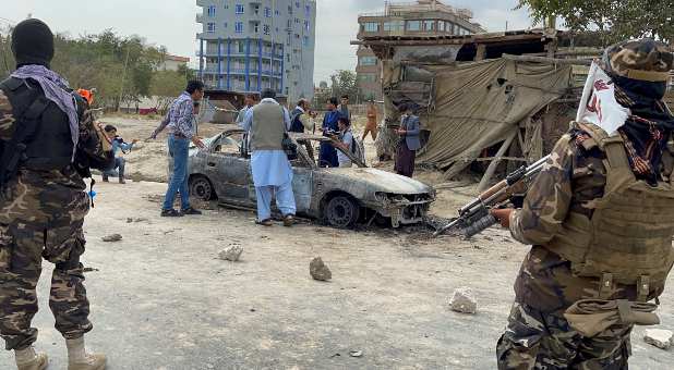 Afghan men take pictures of a vehicle from which rockets were fired, as Taliban forces stand guard, in Kabul, Afghanistan August 30, 2021.