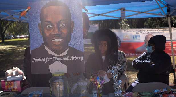 A poster depicting Ahmaud Arbery is seen outside the Glynn County Courthouse while Greg McMichael, his son Travis McMichael and William