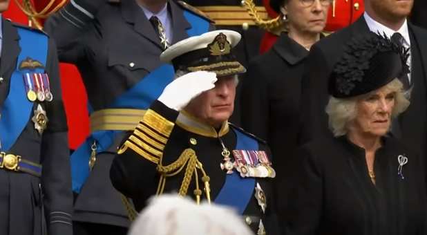 King Charles III salutes his late mother, Queen Elizabeth II, as her coffin heads to St. George's Chapel at Windsor Castle for the committal service.