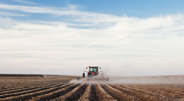 Farmer using a tractor on dry land.