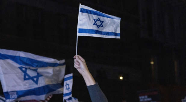 Hand holding an Israeli flag at a rally.