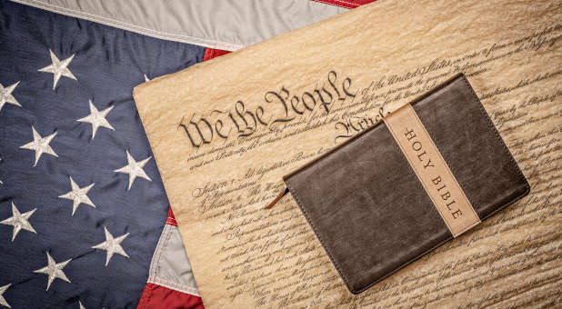 Bible laying on a copy of the U.S. Constitution and an American flag