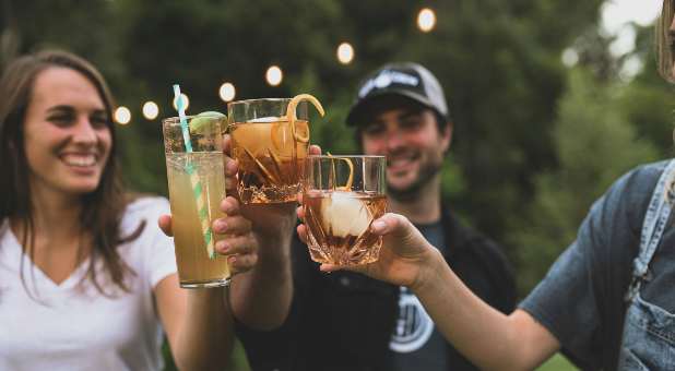 Three individuals toasting with alcoholic drinks.