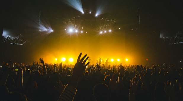 Crowd worshipping in large venue.